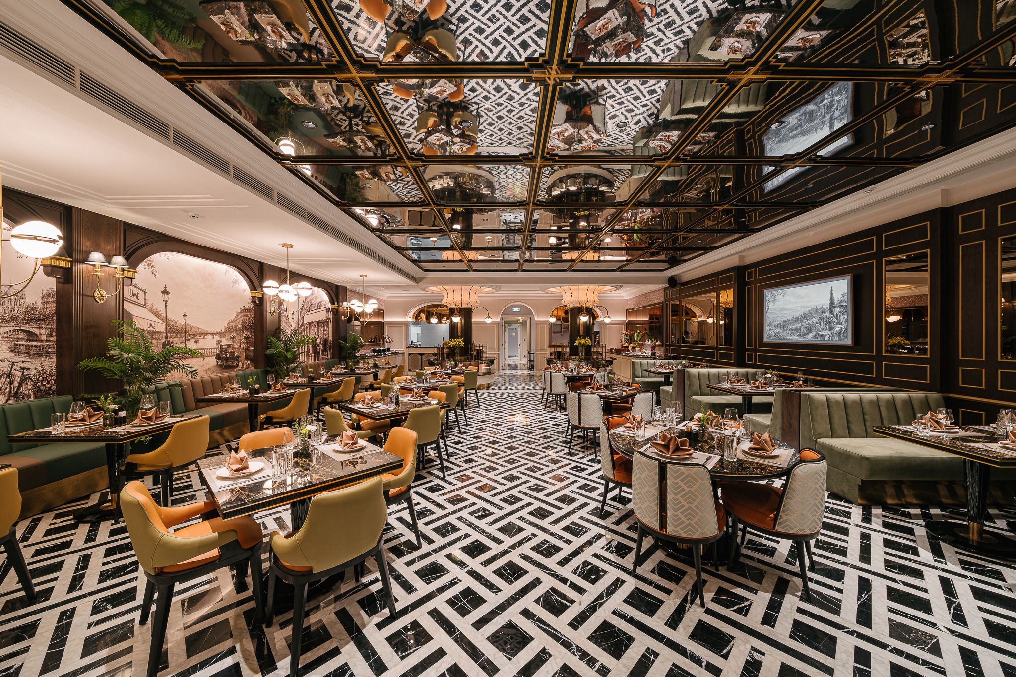 Un comedor amplio con techos altos y decoraciones ornamentales, que incluye varias mesas y sillas.