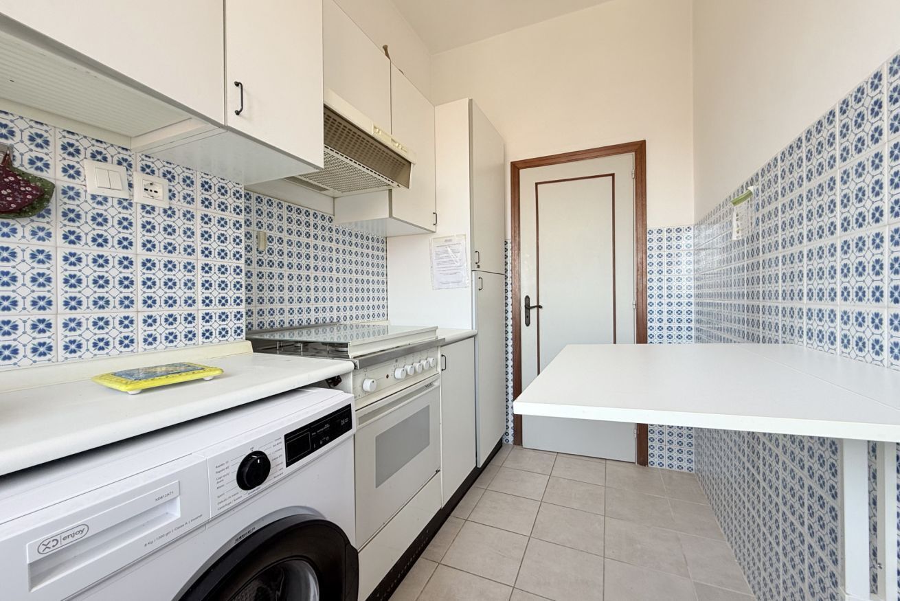 A compact kitchen with a washing machine, a stove, and a sink.