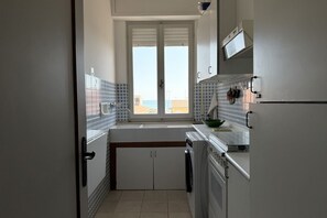 Une cuisine de taille réduite, dotée d’une fenêtre, d’un évier et d’un four à micro-ondes.