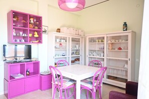 Ein Zimmer mit einem rosa Schrank, einem weißen Tisch und passenden Stühlen.