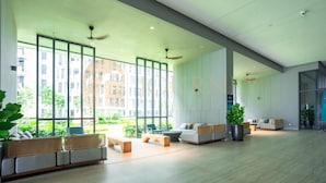 A modern hotel lobby with large windows, seating areas, and ceiling fans.