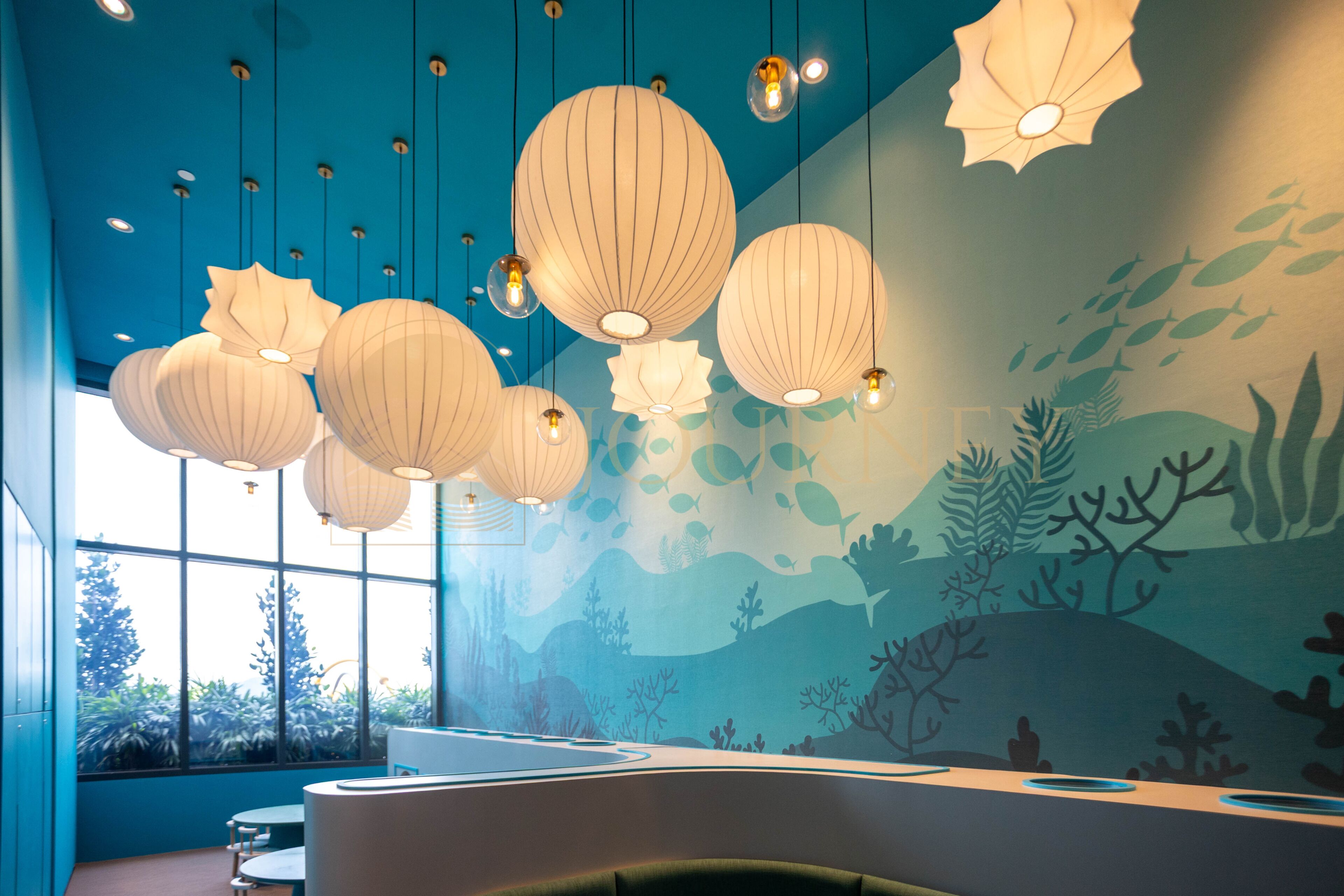 A room with a blue wall, a mural of underwater scenery, and hanging paper lanterns.