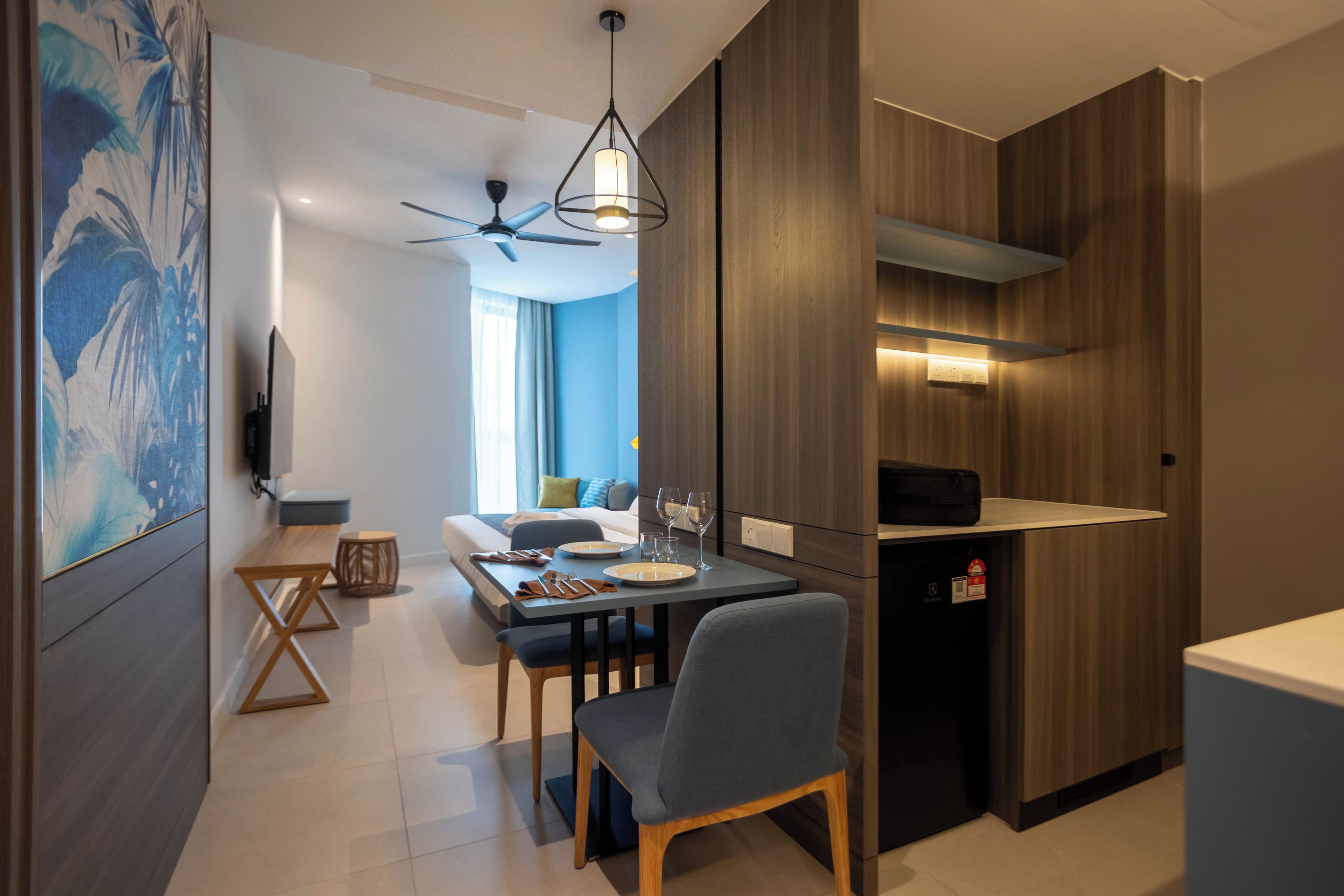 A modern kitchen with a dining area, wooden cabinets, a ceiling fan, and a dining table set for two.