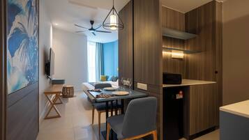 A modern kitchen with a dining area, wooden cabinets, a ceiling fan, and a dining table set for two.