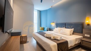 A modern hotel room with a bed, bedside table, lamp, and a wall-mounted TV.