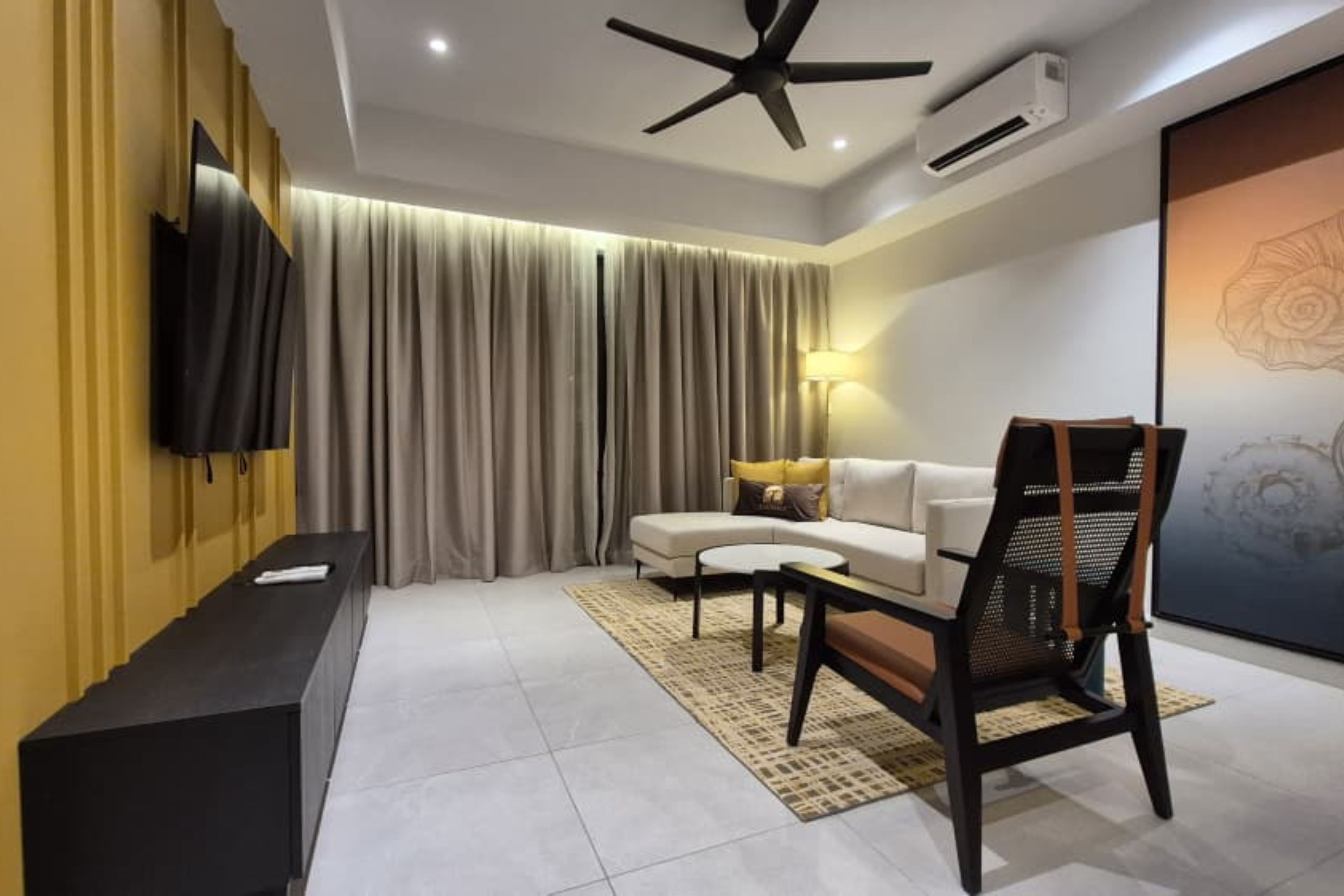 A modern living room with a sofa, a TV, a ceiling fan, and a large painting.