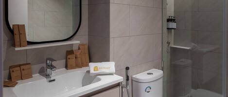 A modern bathroom with a white sink, a large mirror, a shower enclosure, and a toilet.