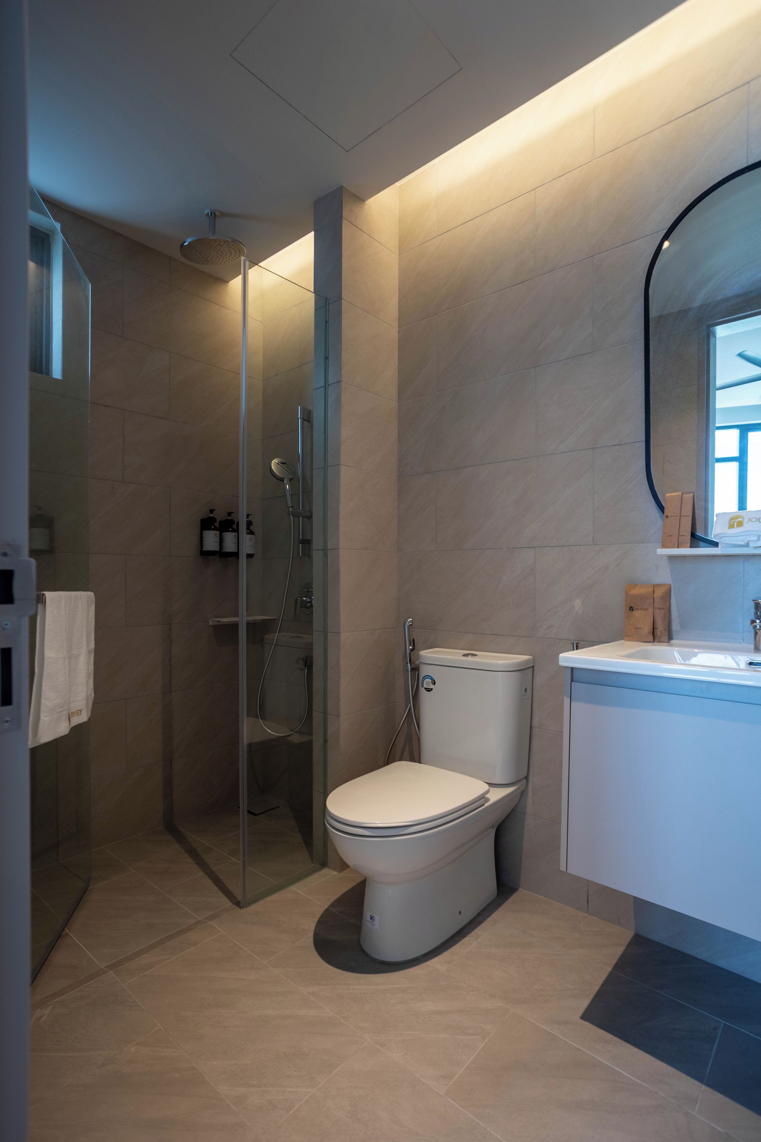 A modern bathroom with a glass-enclosed shower, a toilet, and a sink with a mirror above it.