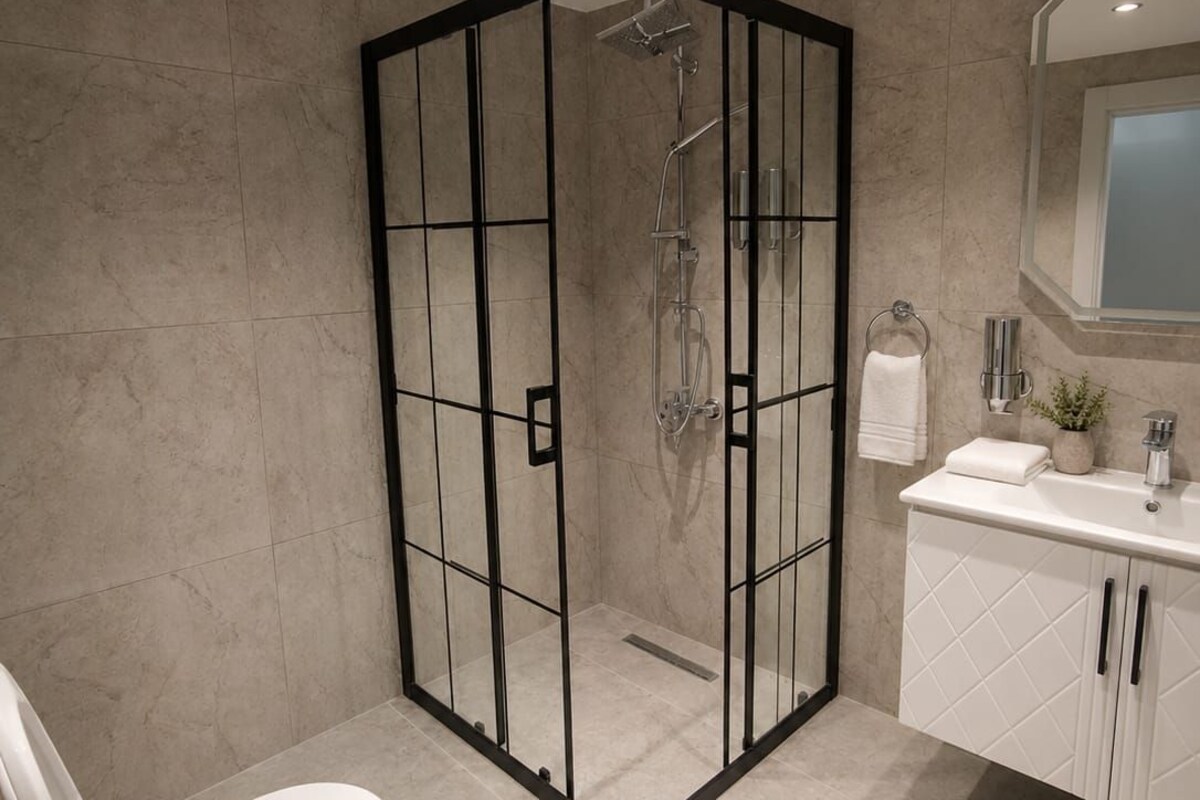 Un baño moderno con ducha de vidrio, inodoro y tocador con espejo.