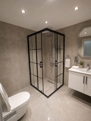 Une salle de bain moderne avec une douche à parois de verre, des toilettes et un meuble-lavabo avec un miroir.