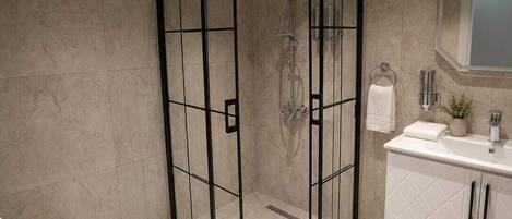 Un bagno moderno con cabina doccia in vetro, un water e un mobile lavabo con specchio.