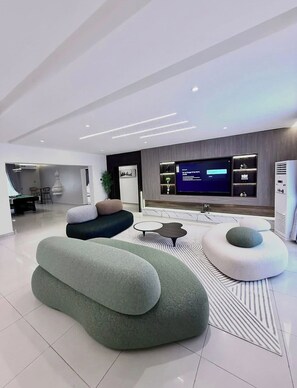 Ein modernes Wohnzimmer mit großem Flachbildfernseher, bequemen Sitzmöglichkeiten und minimalistischem Design.