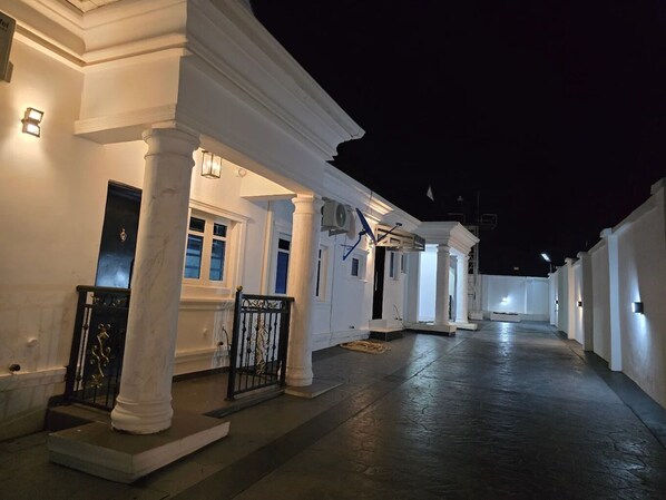 A corridor with white columns, doors, and a gated entrance.