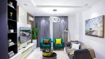 Een moderne woonkamer met een bank, fauteuils, een salontafel en een boekenkast.