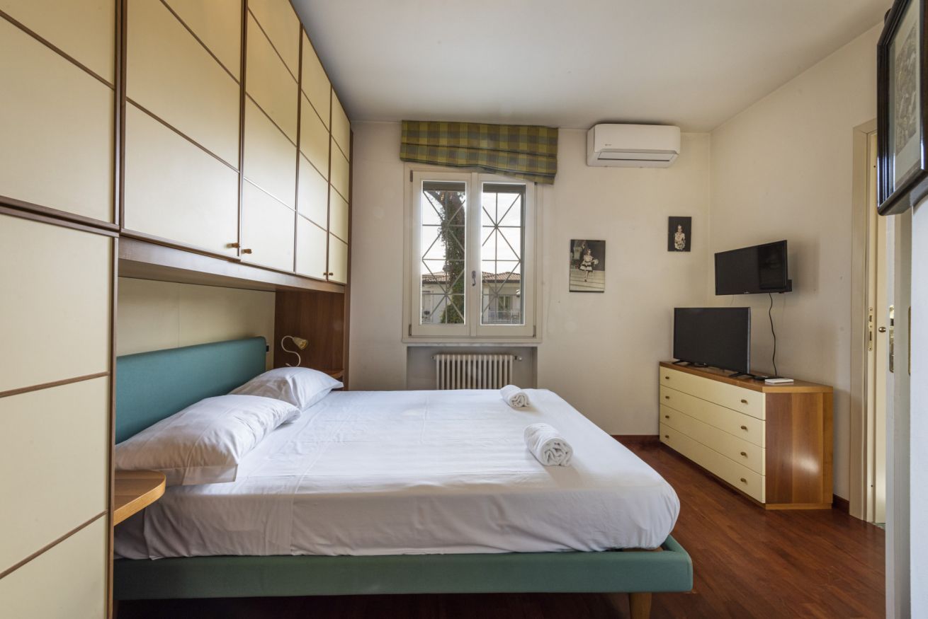 Ein Schlafzimmer mit Bett, Fernseher, Heizkörper und Fenster mit Blick.