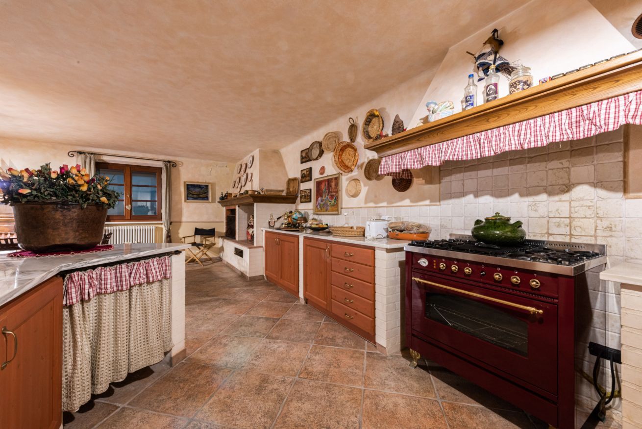 A kitchen with a red stove, wooden cabinets, and a tiled backsplash.