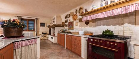 A kitchen with a red stove, wooden cabinets, and a tiled backsplash.
