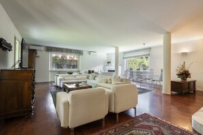A spacious living area with a large sectional sofa, a wooden coffee table, and a decorative rug. - Villa Camillo by MMega (Forte dei Marmi)
