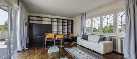 A modern living room with a sofa, a coffee table, and a dining area with chairs.