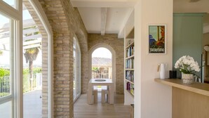 Un corridoio con una parete in pietra, una panca di legno, una libreria e un quadro appeso al muro.