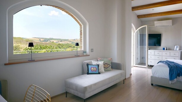 Una camera da letto con un'ampia finestra ad arco, un divano, un letto e una TV.