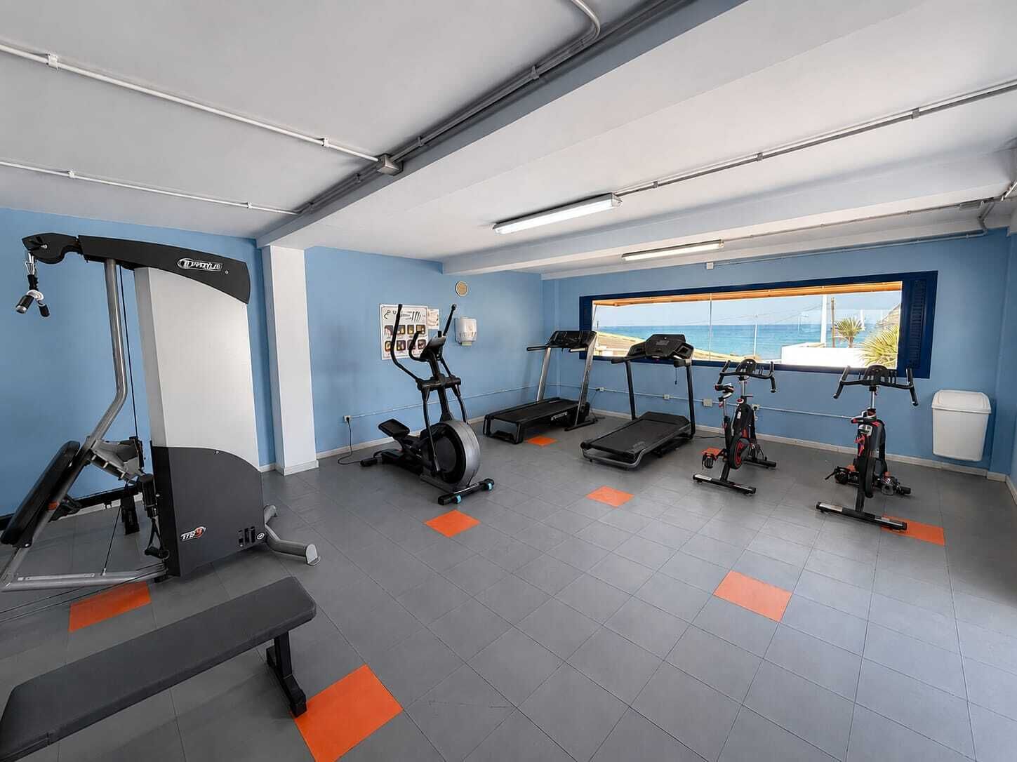 A gym with treadmills, an elliptical, and a bench.