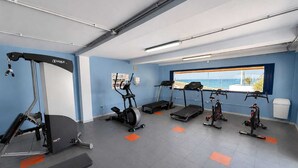 Une salle de sport équipée de tapis de course, d’un appareil elliptique et d’un banc de musculation.