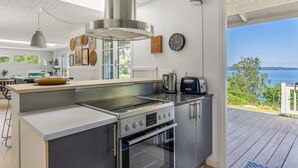A modern kitchen with a built-in stove, oven, and a large window overlooking a scenic view. - "Leea" - 100m from the sea by Interhome (Børkop)