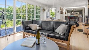 A modern living room with a leather sofa, a dining table with wine glasses, and a telescope on a tripod. - "Leea" - 100m from the sea by Interhome (Børkop)