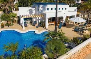 A modern villa with a swimming pool, sun loungers, and a covered outdoor seating area. - Exceptional Villa with Sea Views, Heated Pool, and Inspiring Design (La Sabatera)