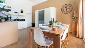 Eine moderne Küche mit integriertem Kühlschrank, einem Essbereich mit Holztisch für vier Personen und einer Wanduhr.