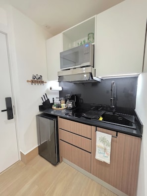 Eine kleine Küche mit Mikrowelle, Kaffeemaschine und kleinem Kühlschrank.