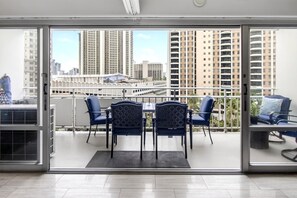 A balcony with a table and chairs, offering a view of high-rise buildings. - Ilikai Luxury Suites | 1-Bd Panoramic Ocean View w Free Parking & Car with 6 nights | ILK-732 by KBM (Honolulu)