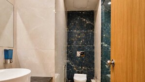 A modern bathroom with a white sink, a toilet, and a shower area. - Soho Suites  (Sukher)