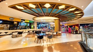 A modern shopping mall interior with a Subway restaurant, a Domino's Pizza, and a children's play area. - Soho Suites  (Sukher)