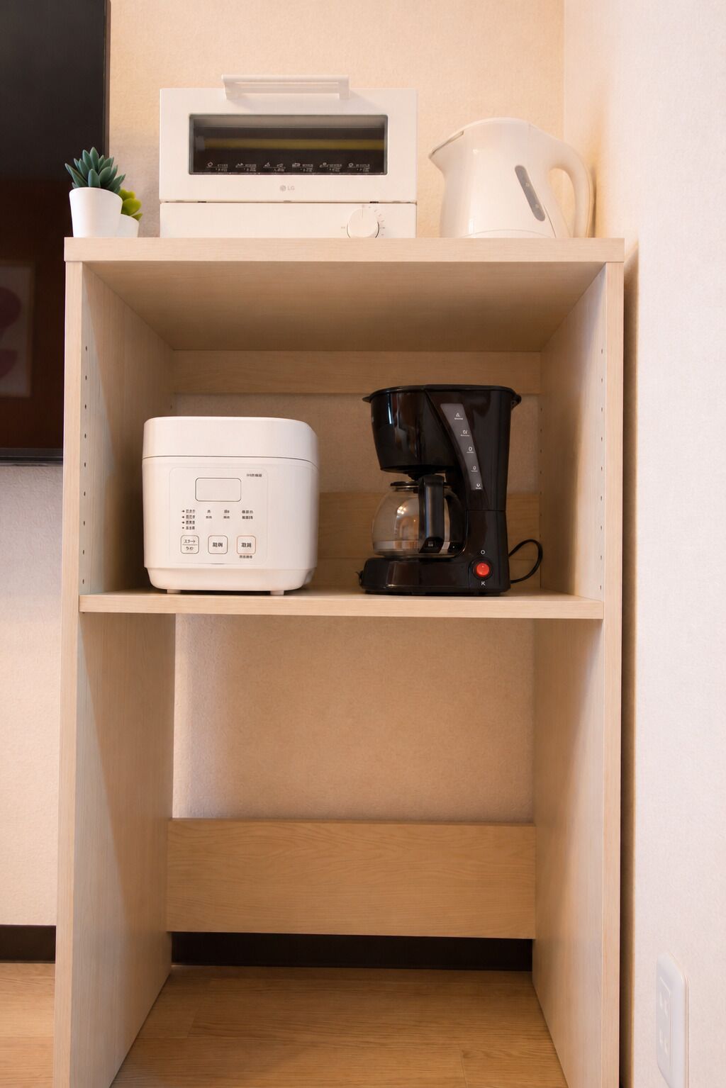 A kitchenette with a coffee maker, a rice cooker, and a small potted plant.