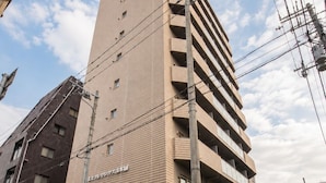 Un immeuble à plusieurs étages doté d’une façade plate, de nombreux balcons et d’une entrée bien visible.