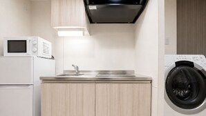 Une cuisine compacte équipée d’un four à micro-ondes, d’un évier et d’un lave-linge.