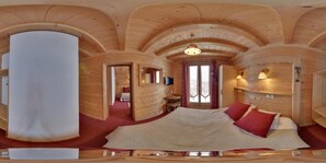 A log cabin room with a large bed, wooden walls, and a ceiling with arched wooden beams. - Hôtel L'Accroche Coeur (Montvalezan)
