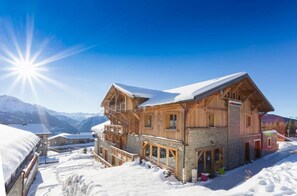 A wooden chalet with a balcony, surrounded by snow-covered mountains. - Hôtel L'Accroche Coeur (Montvalezan)