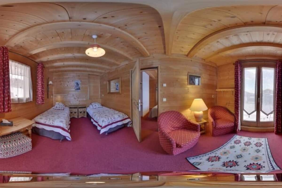 A wooden cabin with two beds, a desk, and a lamp.