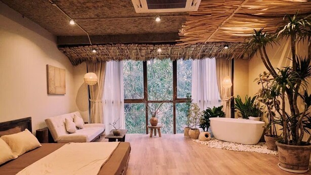A room with a bed, a sofa, a bathtub, and potted plants. - Hideout: Romantic Bathtub Escape at Old Quarter (Hà Nội)
