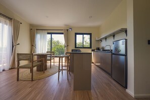 A modern kitchen with a built-in island, a dining area with a table and chairs, and large windows with curtains. - Aloe Valley (Ndaragwa)