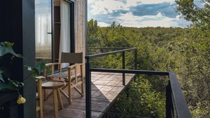 A wooden deck with a table and chairs, overlooking a forested landscape. - Aloe Valley (Ndaragwa)