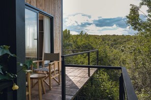 Terraza de madera con mesa y sillas, con vistas a un paisaje boscoso.