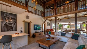 Amplia sala de estar con un sofá grande, una mesa de centro de madera, un televisor y un balcón con mobiliario exterior.