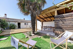 Un molo in legno, una palma, un'area verde e due comode poltrone a righe.