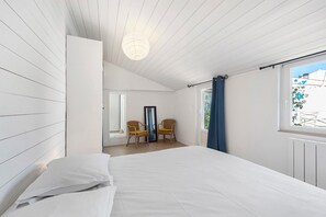 Una camera da letto con un letto, due poltrone, una finestra con tende e una lampada a soffitto.