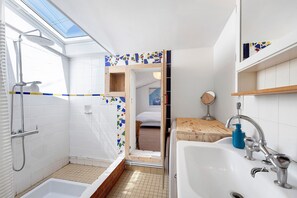 Un bagno con doccia, lavandino e finestra a lucernario.