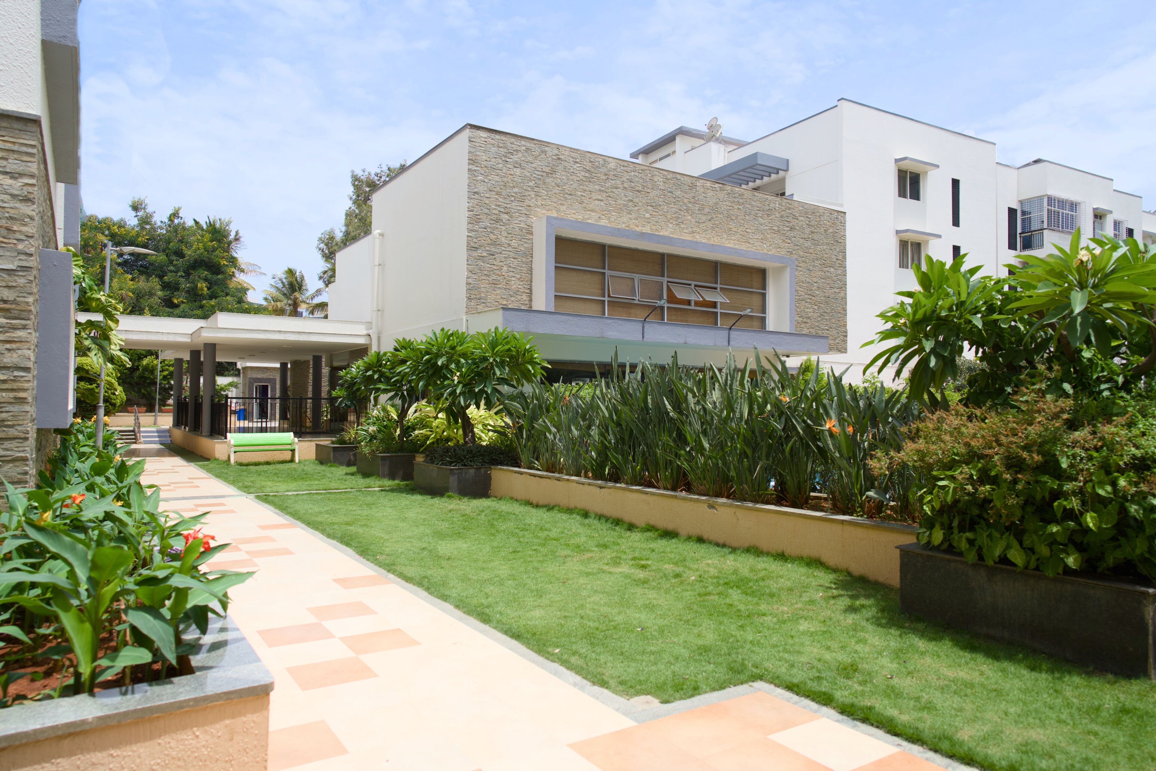 Un bâtiment moderne doté d’un toit plat, d’une entrée abritée et d’un jardin bien entretenu avec un chemin pavé.